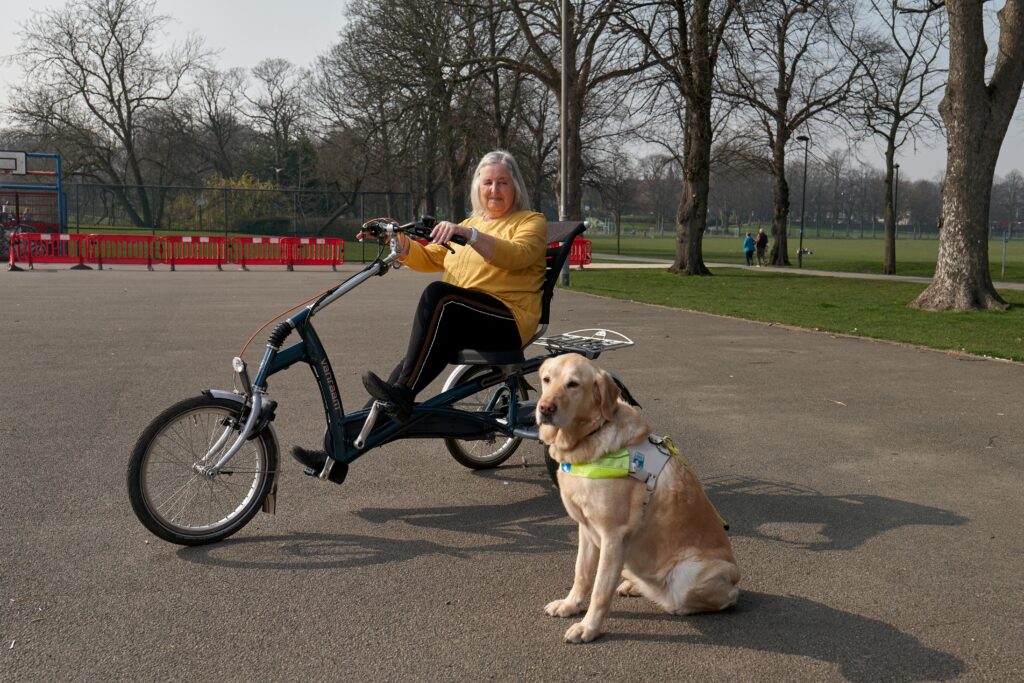Elderly woman with guide dog on an adaptive bicycle in the park.