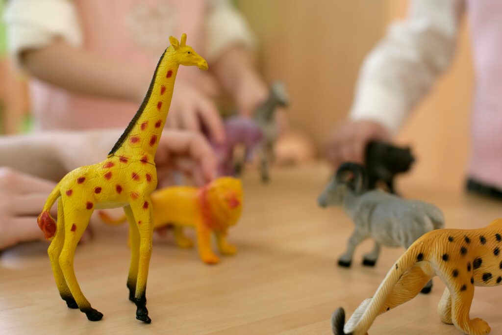 Close-up of children's hands playing with animal plastic toys.